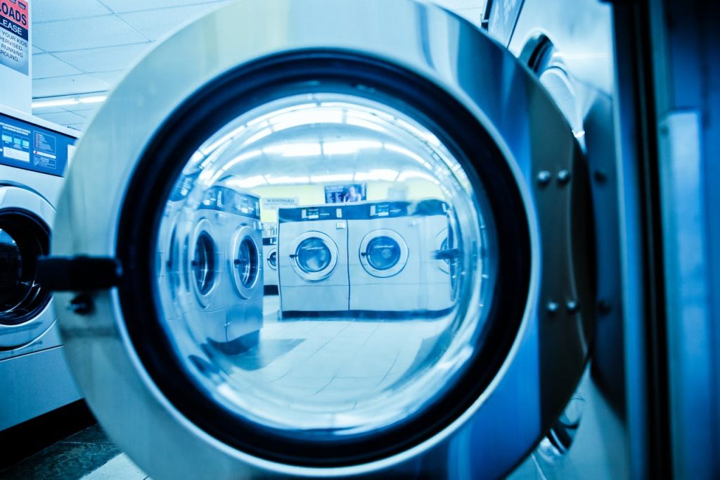pexels-photo-4700611 Interior view of a modern laundromat with rows of steel washing machines.